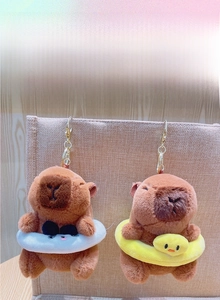Macro shot of Capybara plush pendants with yellow duck and white swim rings and gold clips