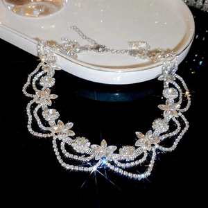 Macro shot of silver crystal flower necklace with diamond-cut petals on white tray