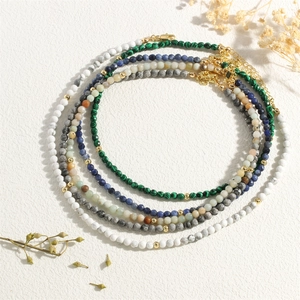 Detail of stacked natural stone necklaces featuring malachite, lapis, and gold beads
