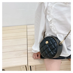 Detail of a kids mini round quilted bag with golden flower accent and chain strap