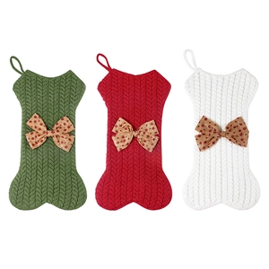 Three knitted bone-shaped Christmas stockings in green, red and white with bows
