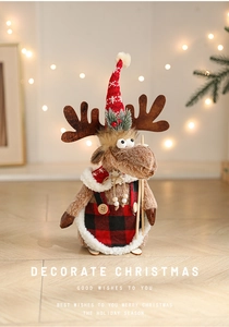 Close-up of Christmas reindeer doll with red hat and plaid apron in warm home lighting