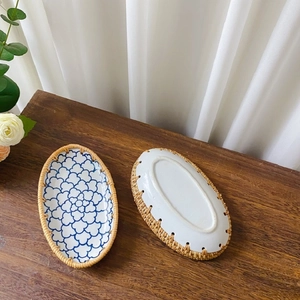 Detail of blue and white glazed ceramic plates with rustic woven rattan edges on wood
