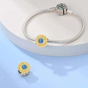 Detail of silver snake chain bracelet with golden sunflower charm and blue starry sky pattern