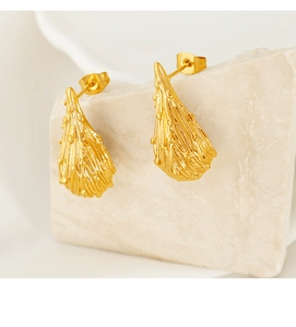 Detailed macro of gold drop earrings with irregular lava texture on stone display