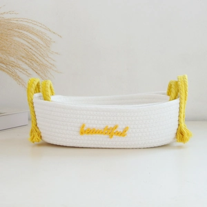 Close-up of white handwoven cotton rope basket with yellow handles and beautiful embroidery