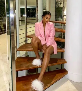 Slim-fit pink blazer dress and feather slippers shown on modern wooden stairs