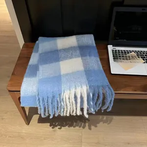 Detail view of soft blue and white plaid scarf featuring elegant long fringe edges