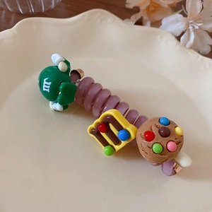 Détail d'un chouchou spirale violet avec des breloques en résine sur une assiette en céramique