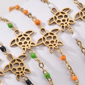 Fashionable gold turtle charm bracelet with colorful beads on a white display stand