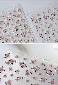 Detailed macro view of 5D embossed nail stickers featuring pink cherry blossoms and green leaves