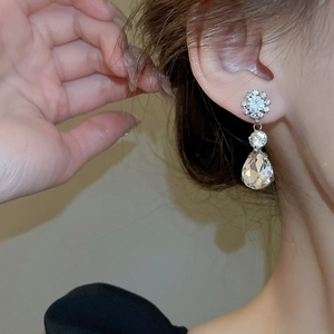 Close-up of elegant silver teardrop crystal earrings worn by a model in soft light