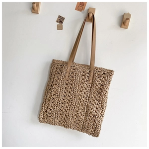 Detail of hollow-out woven pattern and long faux leather straps on a beige tote bag