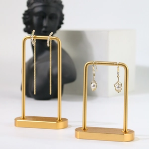 Detail of gold tassel earrings and pearl pendants on U-shaped metal display stand
