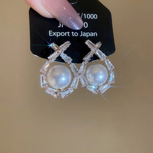 Close-up of pearl drop earrings with rectangular zircon geometric frame on a black card