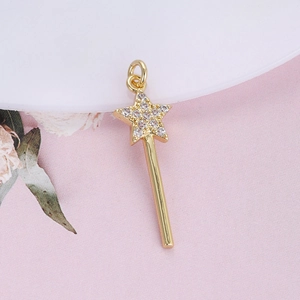 Macro shot of gold star scepter pendant with cubic zirconia on pink fabric background