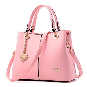 Pink faux leather handbag for women with gold hardware and heart pendant on white background