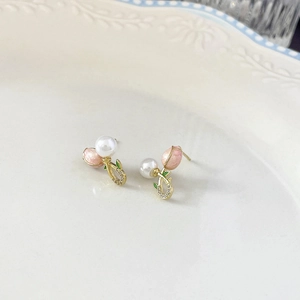 Boucles d'oreilles tulipes roses avec zircons et perles sur une assiette en céramique