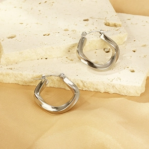Gros plan de boucles d'oreilles rectangulaires torsadées en argent sur pierre élégante