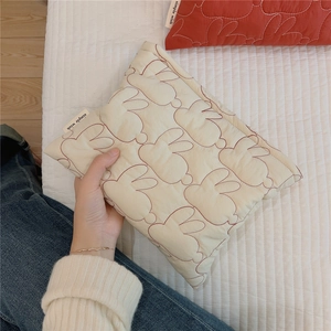Close-up of quilted cream cotton makeup bag featuring red rabbit outline patterns