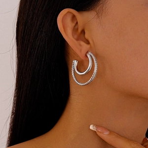 Detail of silver C-shaped double-layer hoop earrings with textured outer band on model