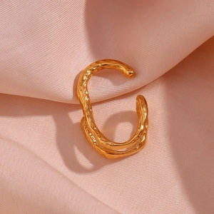 Detail of 18K gold-plated ear cuff featuring irregular hammered texture on pink silk fabric