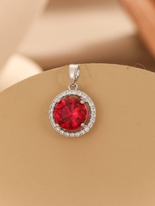 Macro shot of a four-claw red zircon pendant with a sparkling white gemstone halo