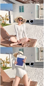 Detail showing white long-sleeved swimsuit texture with vertical stripe fabric on beach