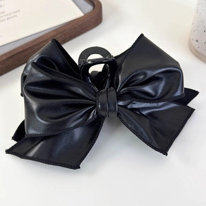 Close-up of black PU leather bow hair claw clip showing fine texture and stitching details