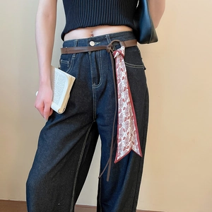 Close-up of brown leather belt with red and white paisley silk scarf fringe on jeans