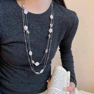 Detail of multi-layer silver necklace with irregular white beads on a female model