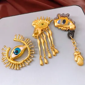Vintage surrealist gold eye brooches with blue rhinestones and dangling tassels