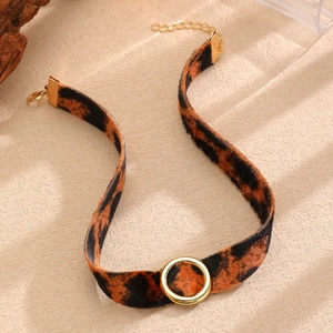 Dettaglio di un choker in velluto leopardato con anello circolare in metallo dorato