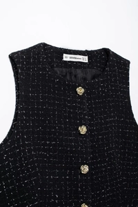 Gros plan sur un gilet en tweed noir avec boutons dorés gaufrés et texture de tissu premium