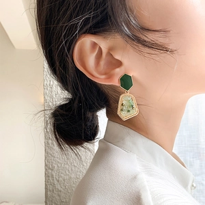 Retro geometric earrings with green crushed stone inlays and gold plating on a model