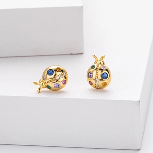 Macro shot of gold ladybug stud earrings with multicolored gemstones and zircon accents