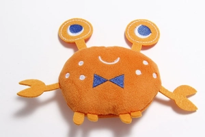Detail shot of orange crab plush pet toy featuring blue embroidery and soft fleece texture