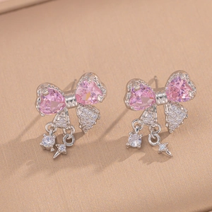 Detail of silver bow earrings featuring pink heart stones and zircon fringe tassels