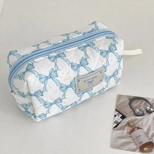 Detail of white quilted makeup bag with blue bow patterns and Good night label