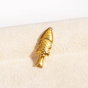 Detailed view of a golden fish pendant with scale textures on beige fabric