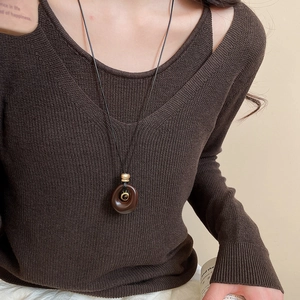 Detail of resin tiger eye oval pendant necklace worn on a vintage brown knit sweater