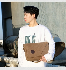 Outdoor street style shot of brown canvas messenger bag worn by a male model
