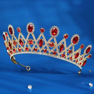 Detail view of gold baroque bridal crown with red gemstones and crystals on blue background
