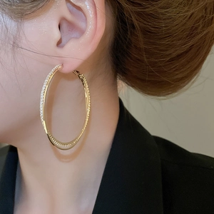 Close-up of elegant gold double intertwined hoop earrings with sparkling rhinestones on model