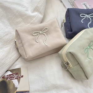 Detailed close-up of bowknot embroidery on premium canvas cosmetic bags with metal rings