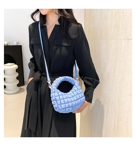 Detail view of a light blue quilted nylon dumpling bag with textured puffy finish