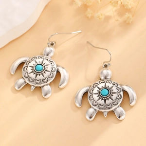Close-up of vintage silver turtle earrings with turquoise stone and tribal sun pattern