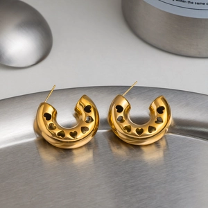 Detailed view of vintage gold hollow heart C-shaped hoop earrings on metal tray