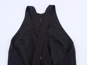 Detail van zwarte halter mini-jurk met gekruist ontwerp en een stijlvolle metalen gesp