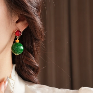 Détail d'une boucle d'oreille pendante en céramique rouge et verte de style vintage